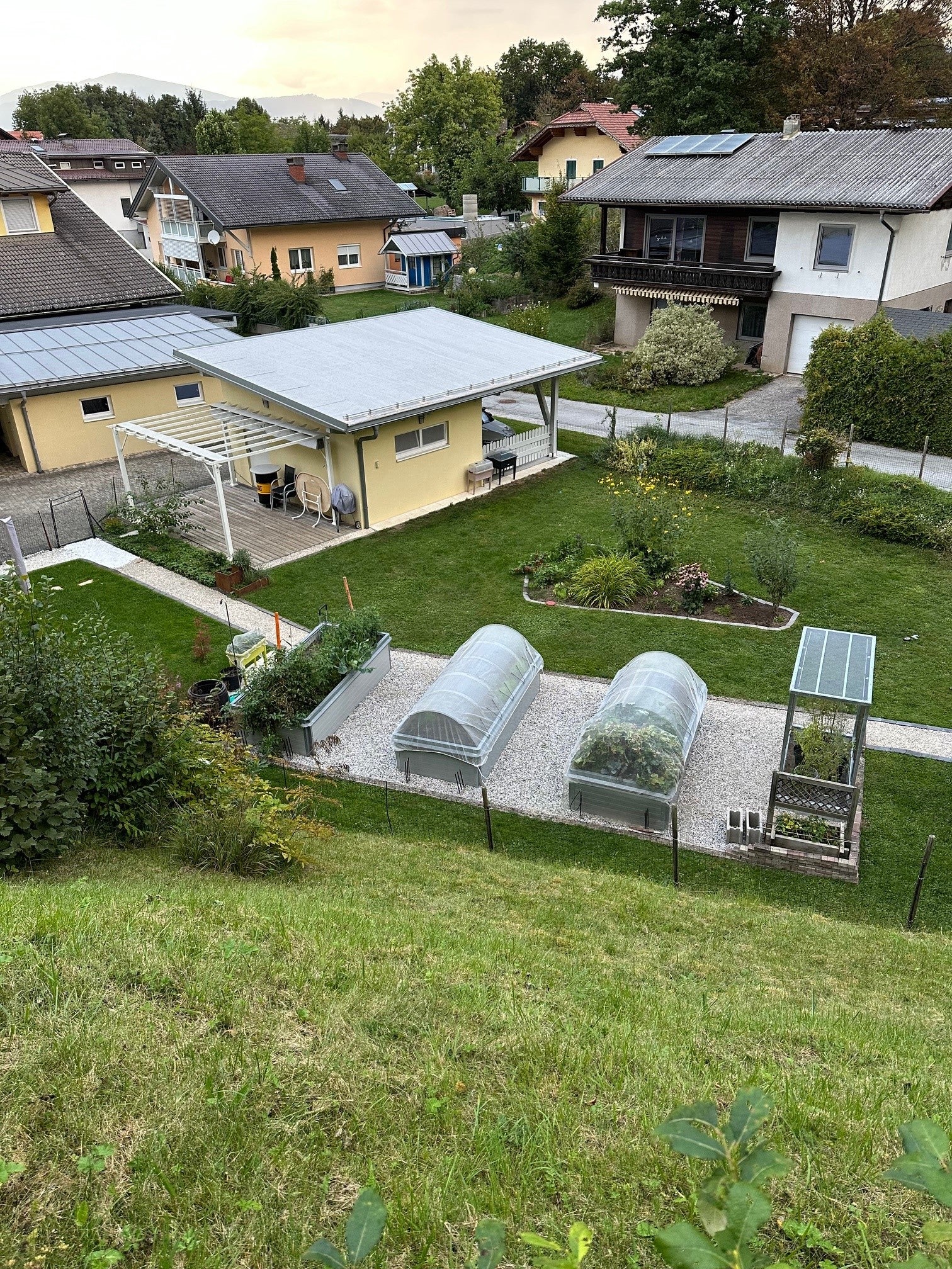 Gartensansicht mit Hochbeeten und Tomatenhaus